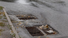 Flow Of Water During Heavy Rain And Clogging Of Street Sewage. The Flow Of Water During A Strong Hurricane In Storm Sewers. Sewage Storm System Along The Road To Drain Rain Into The Drainage System