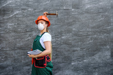 Woman Worker In Coverall With Tool Belt Posing Near Grey Wall