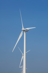 A Modern Wind Farm consisting of Wind Turbines with Two and Three Blades along the Shore of Veluwemeer under Partly Cloudy and Blue Sky in the Netherlands