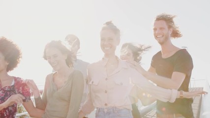 Wall Mural - Group Of Young Friends Outdoors Walking Across Bridge Together Against Flaring Sun