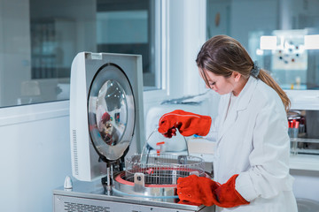 Wall Mural - young female scientist standing in her lab using the autokey or autoclave. sterilize material in lab