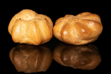 Group of two whole fresh baked golden profiterole isolated on black glass