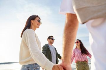 Sticker - friendship, leisure and people concept - group of happy friends holding hands on beach in summer