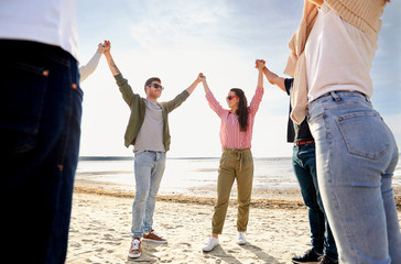 Sticker - friendship, leisure and people concept - group of happy friends holding hands on beach in summer