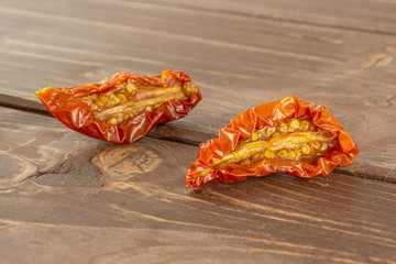 Group of two slices of dry red cherry tomato on brown wood