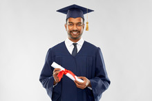 Education, Graduation And People Concept - Happy Smiling Indian Male Graduate Student In Mortar Board And Bachelor Gown With Diploma Over Grey Background