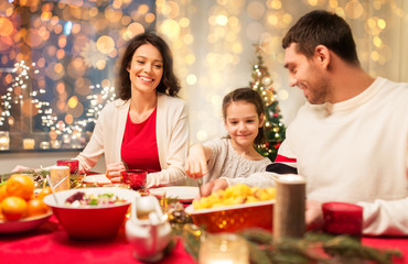 Canvas Print - holidays, family and celebration concept - happy mother, father and little daughter having christmas dinner at home