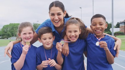 Wall Mural - Children With Female Coach Showing Off Winners Medals On Sports Day