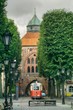 ulica w centrum starego Słupska, gotycka brama miejska, dawne więzienie, obecnie galeria sztuki Nowa Brama, zabytkowy tramwaj na torze