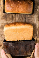 Two loaves of white bread on an oak board