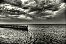 Breathtaking Beautiful Shot Of The Stormy Sea With The Stone Pier On The Side And Dark Clouds Above