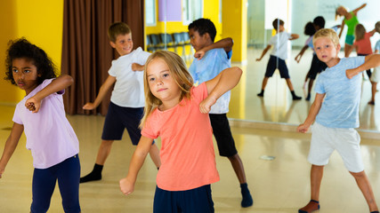 Wall Mural - Portrait of smiling children practicing sport dance in modern dance hall