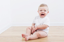 Baby Crying Sitting On Wooden Floor