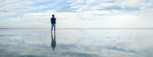 Man In The Water At Sea. Concept Of A Happy Holiday And Freedom. Tourist Looking At The Horizon Line. Beautiful Panorama Of The Salt Lake With The Reflection Of White Clouds In The Ode.