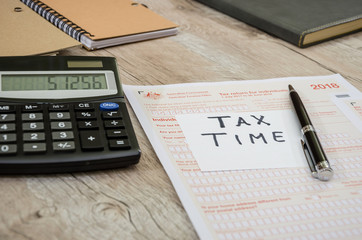 Australian tax forms, calculator, notebooks and pen on the table.