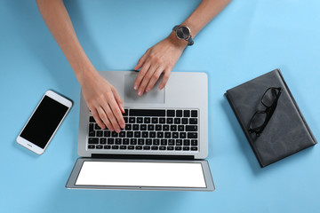 Young woman using laptop on light blue background, top view