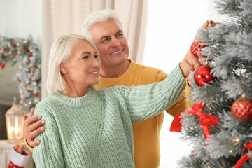 Wall Mural - Happy mature couple decorating Christmas tree at home