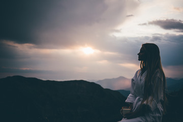 Side view woman in SPA bathrobe standing in the beautiful mountain view at the sunset. Travel and healthy lifestyle and beauty outdoors.