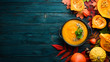 Pumpkin soup with pumpkin and colored autumn leaves. flat lay. On a blue wooden background. Top view. Free space for your text.
