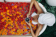 © Alena Ozerova - Woman relaxing in outdoor bath with flowers in Bali spa hotel.