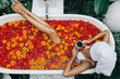 © Alena Ozerova - Woman relaxing in outdoor bath with flowers in Bali spa hotel.