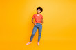Full length body size photo of cool swag good black millennial girl posing in front of camera showing her coolness wearing jeans denim sneakers isolated over vibrant color background