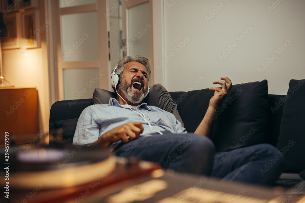 mid aged man relaxing home and listening music on record player - obrazy, fototapety, plakaty 