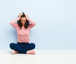 © kues1 - young pretty woman feeling stressed and frustrated, raising hands to head, feeling tired, unhappy and with migraine sitting on floor