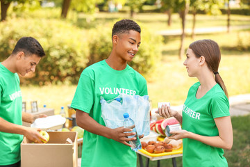 Wall Mural - Young volunteers with food for poor people outdoors