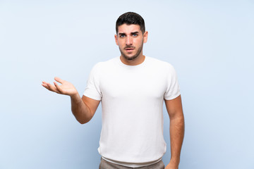 Caucasian handsome man over isolated blue background making doubts gesture