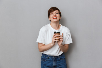 Wall Mural - Image of pretty brunette woman smiling and holding takeaway coffee cup