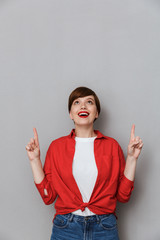 Wall Mural - Image of caucasian brunette woman pointing fingers upward at copyspace