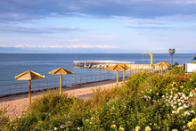 View Of Issyk-Kul Lake, A Beach With View Of Issyk-Kul Lake With Parasols And Lawns With Flowers