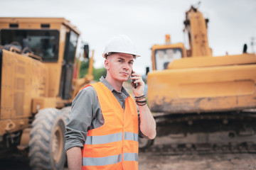 portrait of caucasian engineers using smartphones in the workplace. engineers wear helmets and use p