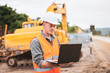 © Pituk - Caucasian young engineer using a laptop on road construction site. Engineer work concept