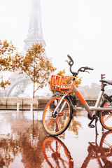 orange bike in the rain on a wet stone street against the backdrop of the eiffel tower in paris