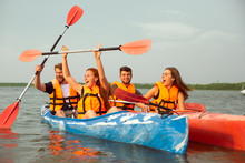 Happy Young Caucasian Group Of Friends Kayaking On River With Sunset In The Backgrounds. Having Fun In Leisure Activity. Happy Male And Female Model Laughting On The Kayak. Sport, Relations Concept.
