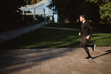 Young handsome stylish sporty man on morning run in park