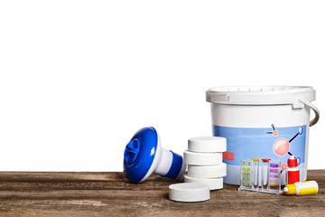 Equipment with chemical cleaning products and tools for the maintenance of the swimming pool on a wooden surface against white background.