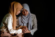© rachaphak - Young muslim women sitting and hold her friend hand as a console. Friends are together when someone having a life issue or problem.
