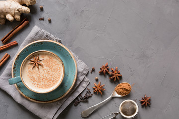 Wall Mural - Masala Indian tea in cup with spices on grey concrete table. Top view.