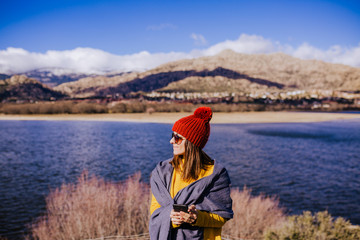 young caucasian woman on the mountain in sunny day using mobile phone. Beautiful lake background view. Nature concept