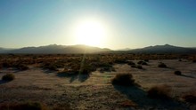 Bright Sun Setting In Mojave Desert, Aerial Pull Back Over Golden Scrub