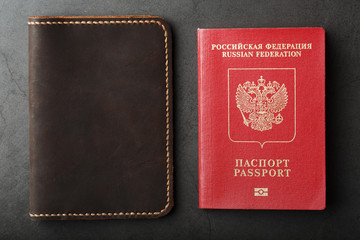 Brown leather cover with a red passport on a dark background