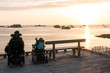 two people in wheelchairs enjoy the opportunity to watch a sunset over the beach and ocean