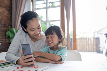 elearning of mother showing her daughter from smartphone during homeschooling activity at home