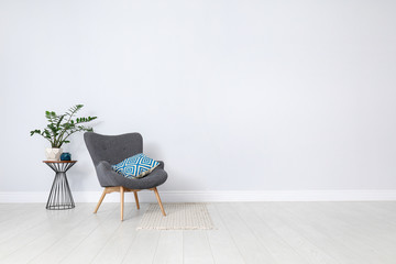 Poster - Stylish room interior with comfortable armchair and plant near white wall. Space for text