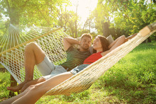 Young Couple Resting In Comfortable Hammock At Green Garden