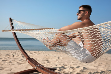 Wall Mural - Young man relaxing in hammock on beach