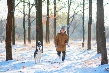 Wall Mural - Boy is running with husky on a distillation in a winter park